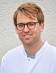 junger Arzt mit Brille in weißem Kittel, hautklinik rostock