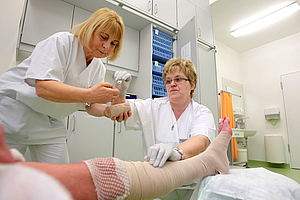 Zwei Krankenschwestern verbinden ein Bein, Hautklinik Unimedizin Rostock 